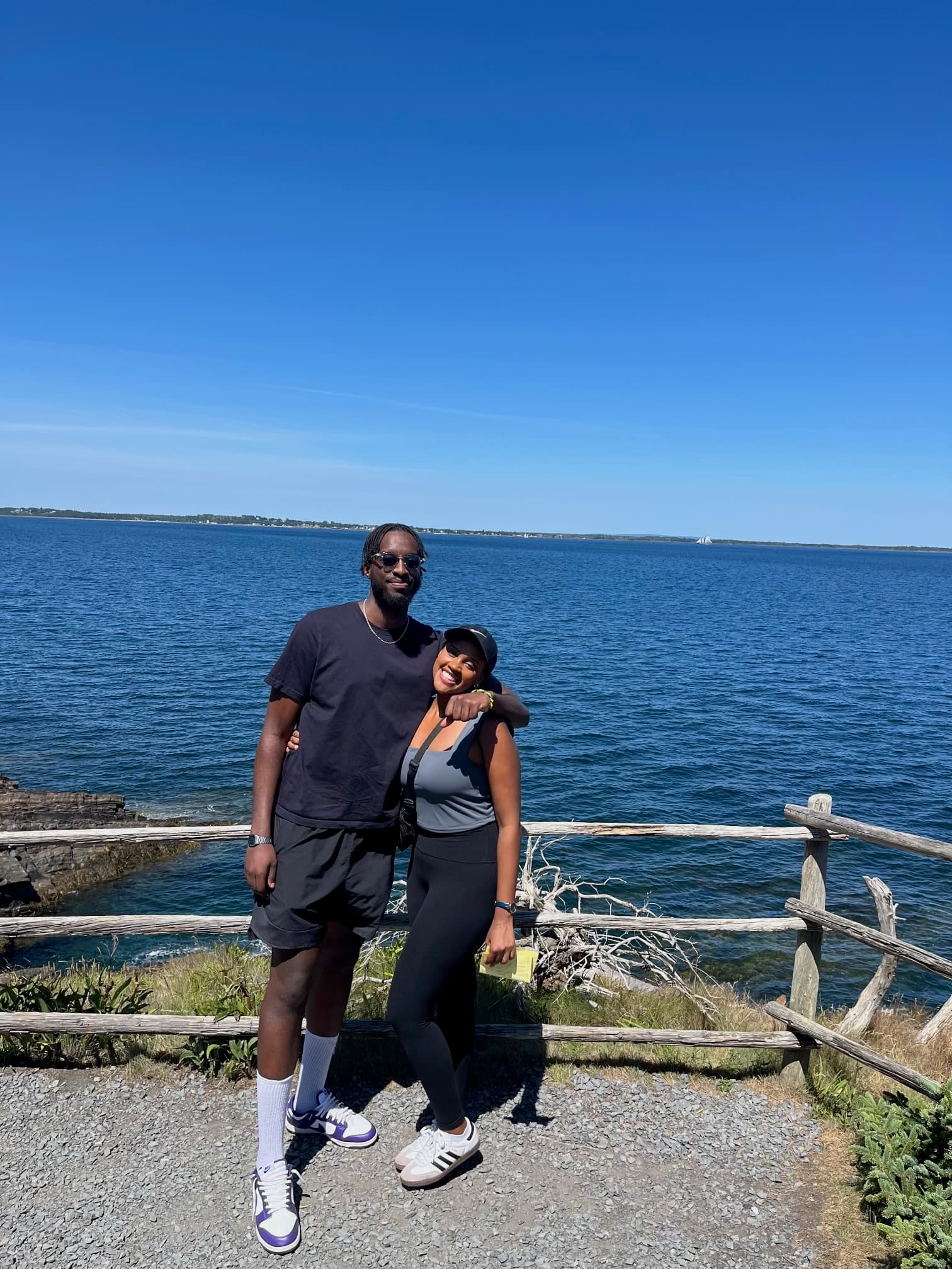 Joshua and Sandrine standing together by the water on a sunny day