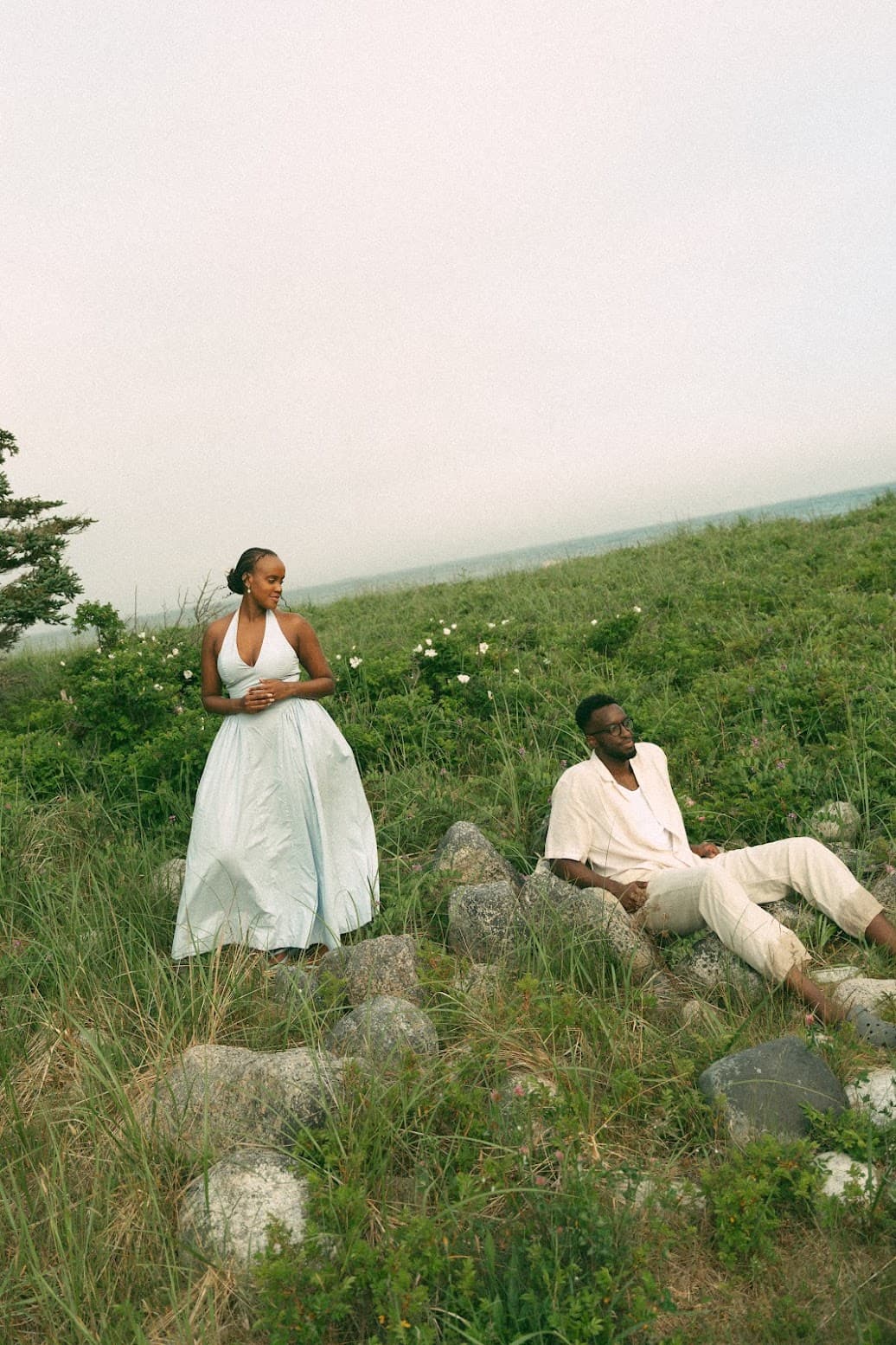 A couple dressed in white on a grassy hillside